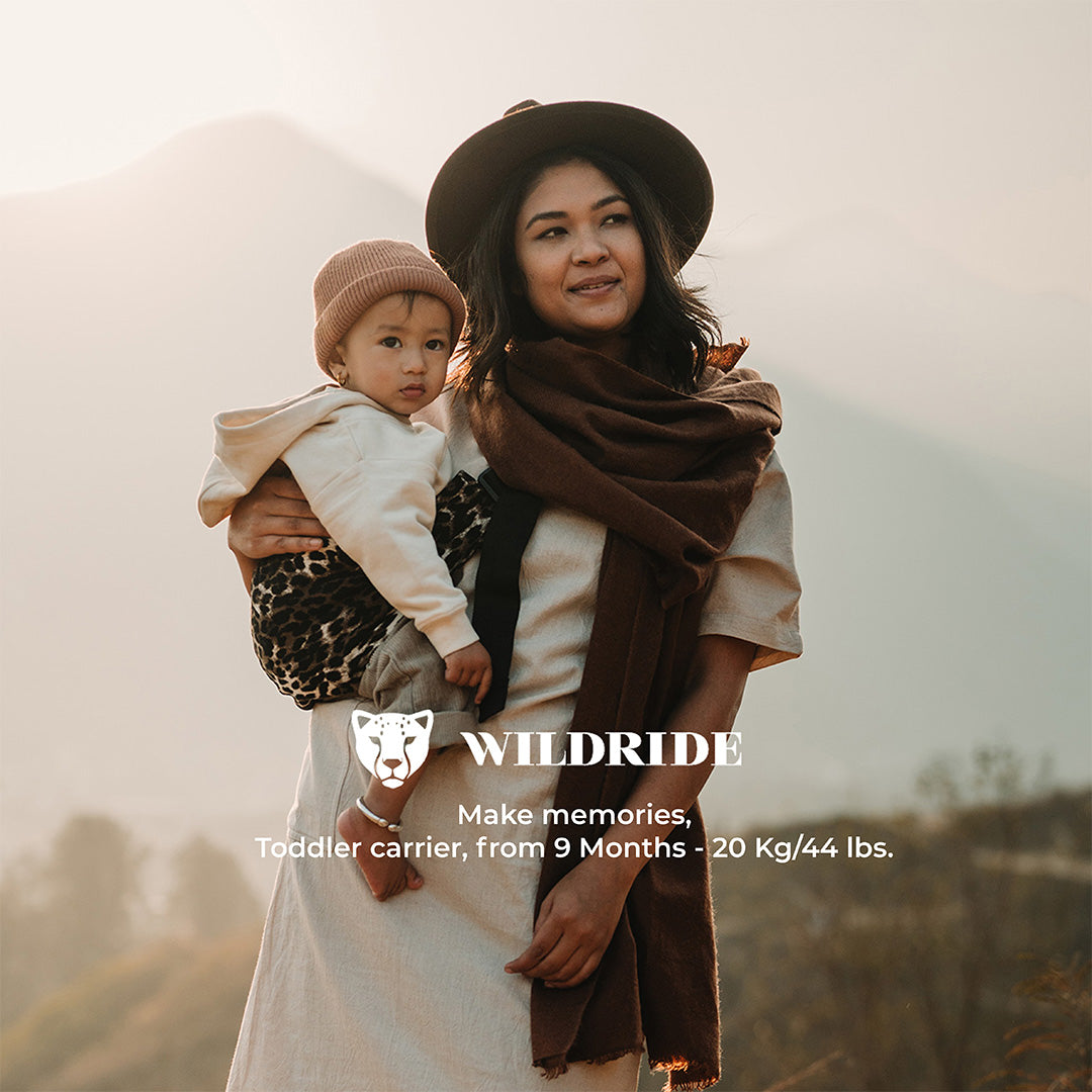 Woman holding a child in a field with 'Wildride' branding.
