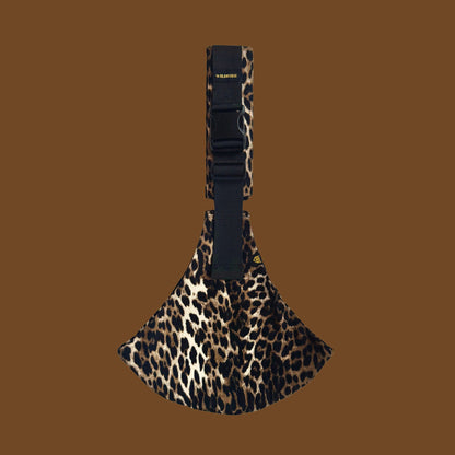 Leopard print toddler carrier with black strap on a brown background