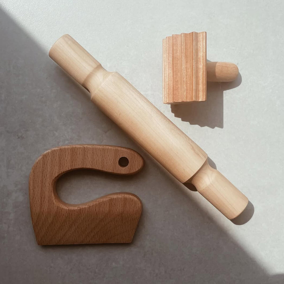 Wooden rolling pin and two wooden tools on a gray surface