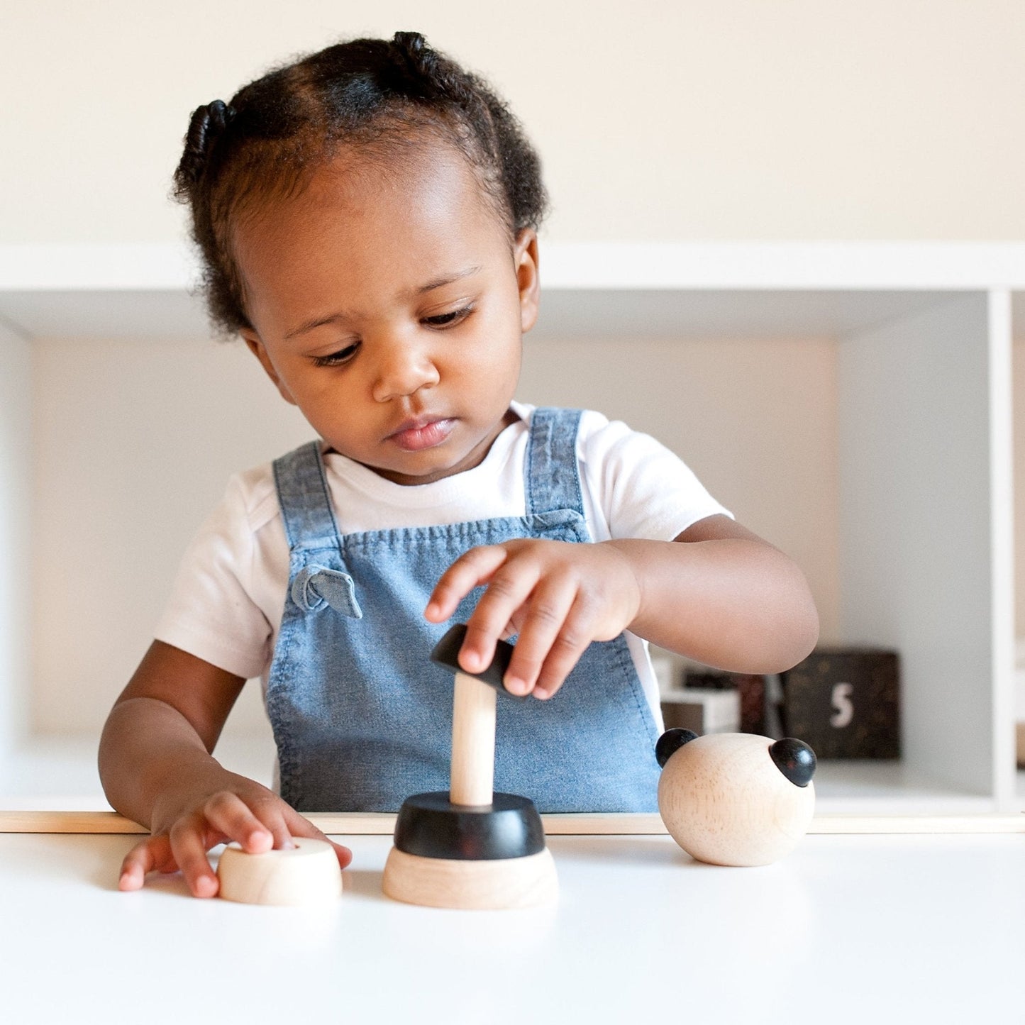 Child playing with wooden toys on a white surface